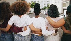 Rearview shot of a group of unrecognizable young friends walking with their arms around each other in the city