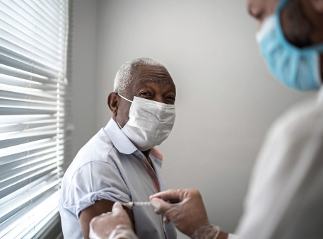Nurse applying vaccine on patient's arm using face mask
