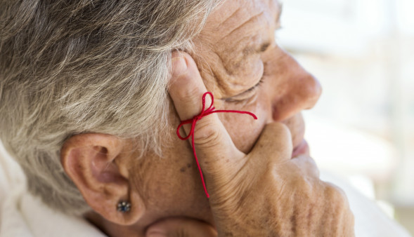 old woman with red string tied around index finger