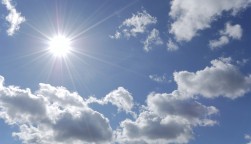 bright sun shining in blue sky with white clouds